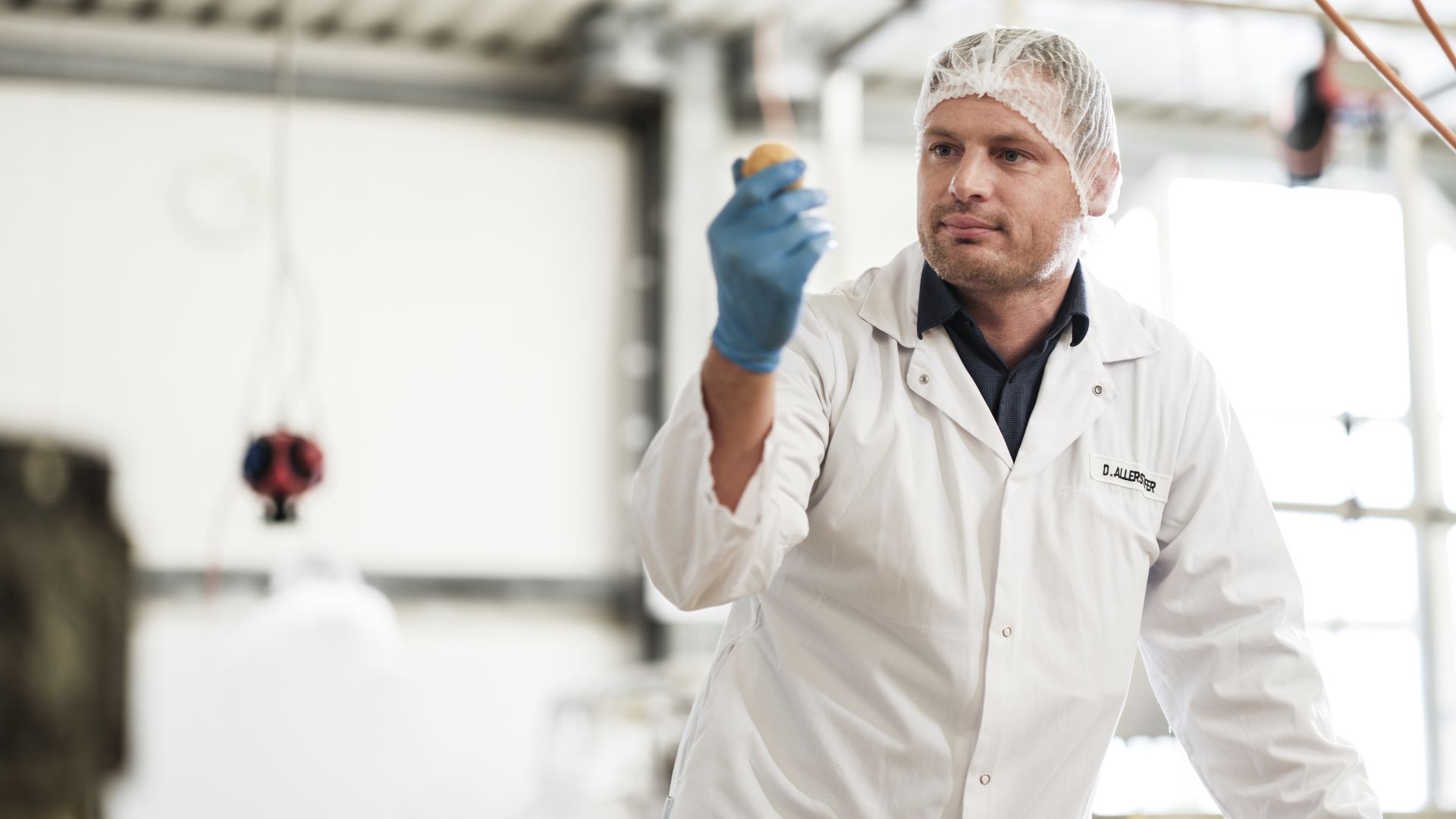 Ein Mann in einem weißen Kittel sieht sich ein Knödel aus der Nähe an